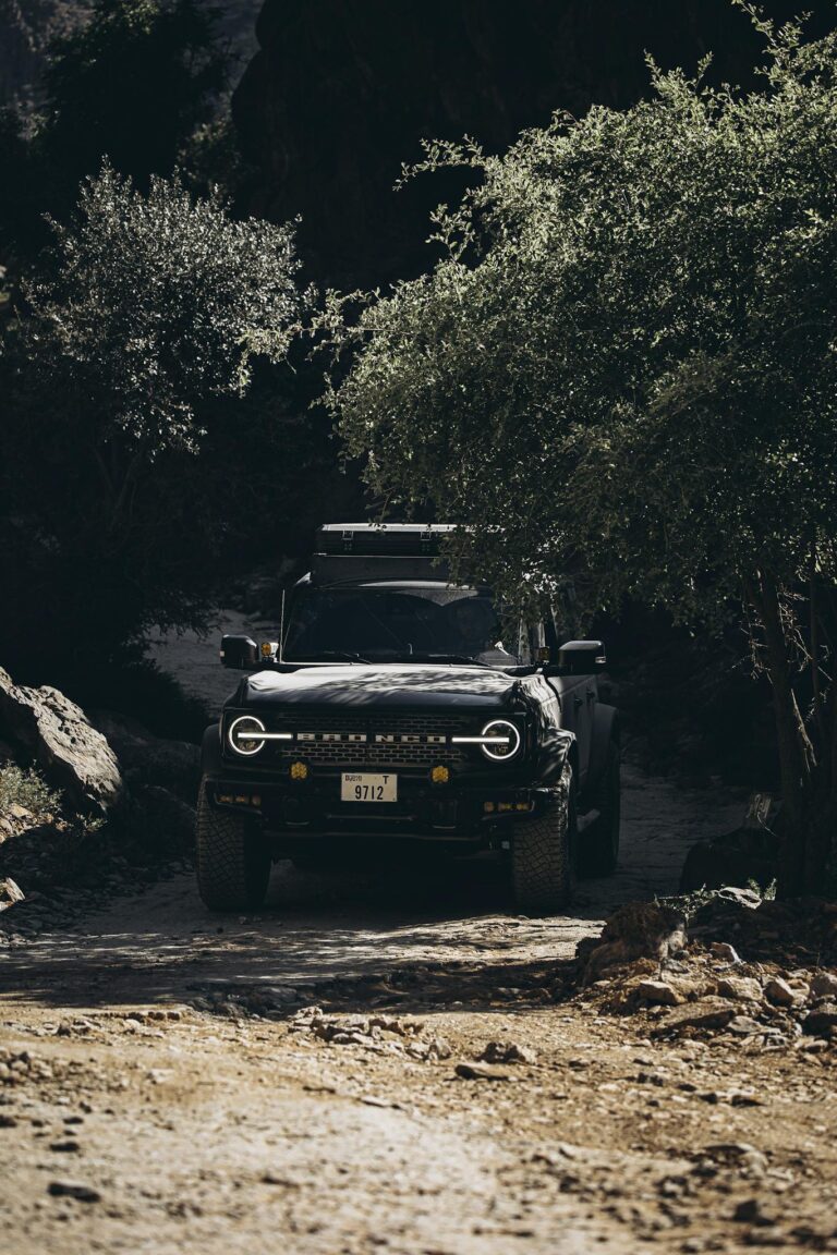 A rugged off-road vehicle navigating a rocky trail in the scenic landscapes of Oman.