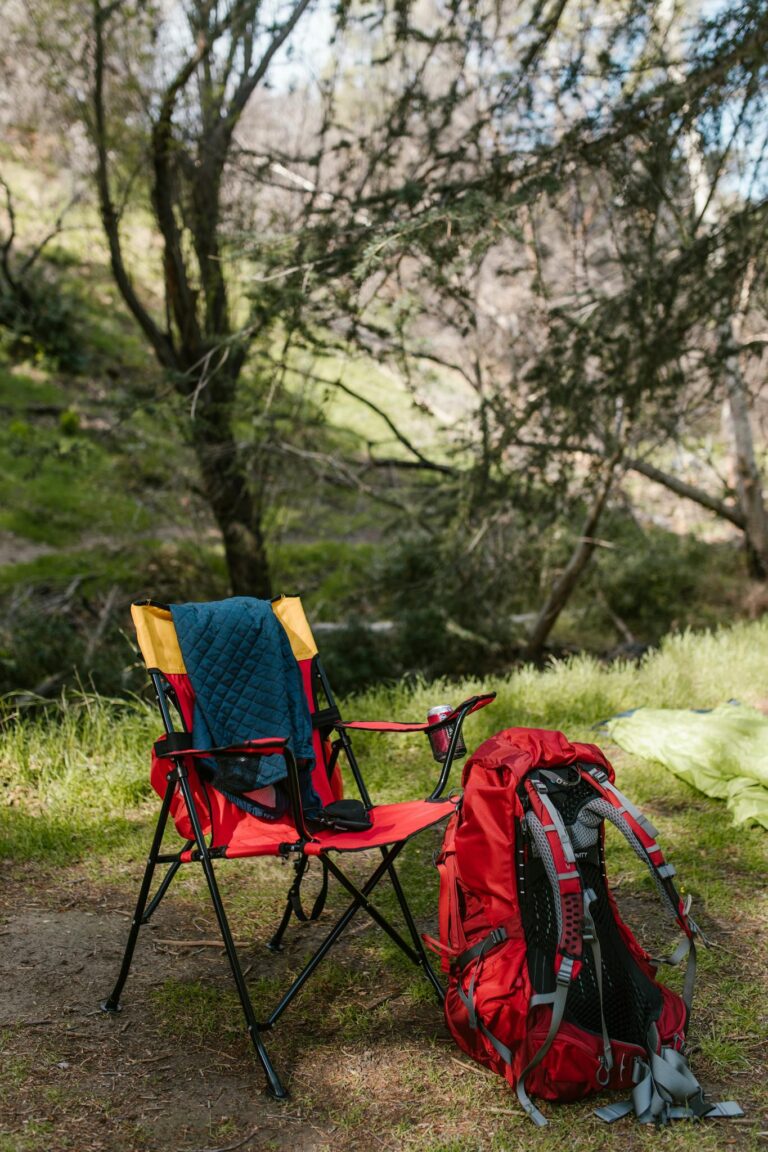 Colorful camping chair and backpack set in a serene forest environment, ideal for outdoor exploration.