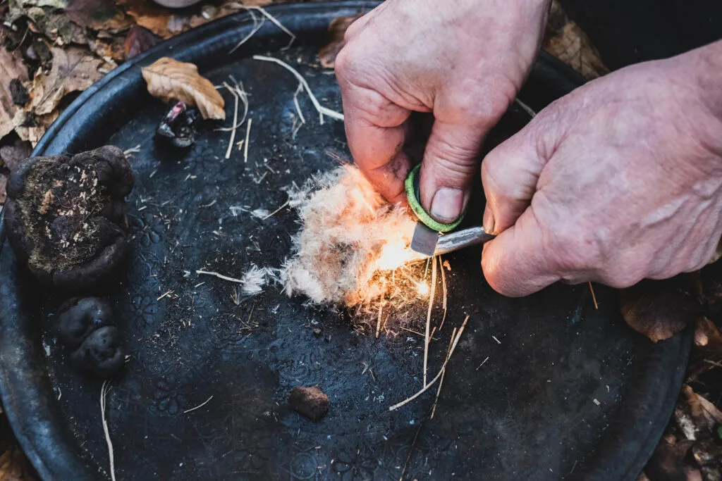Close-up of hands igniting tinder to start a fire