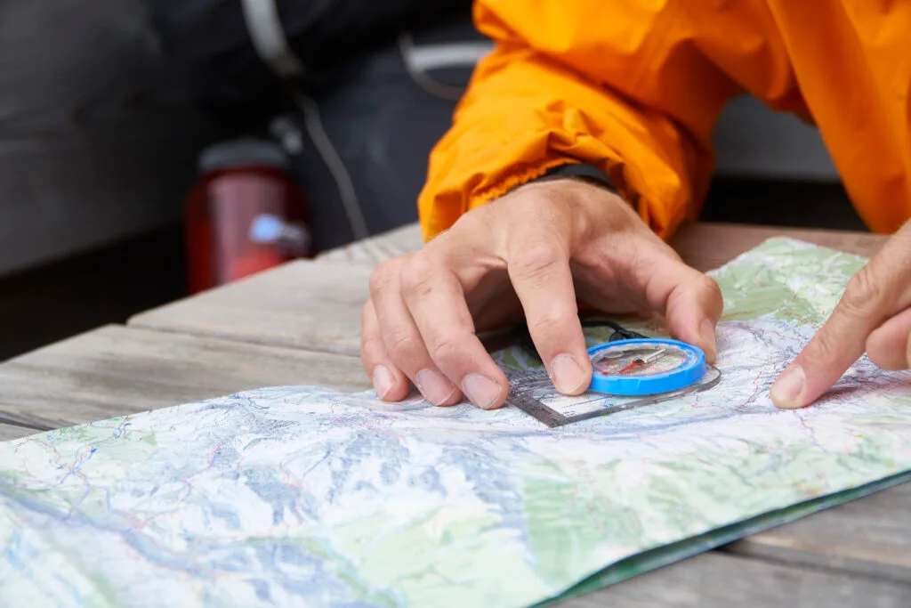 Hiker holding a map and compass together to take a bearing