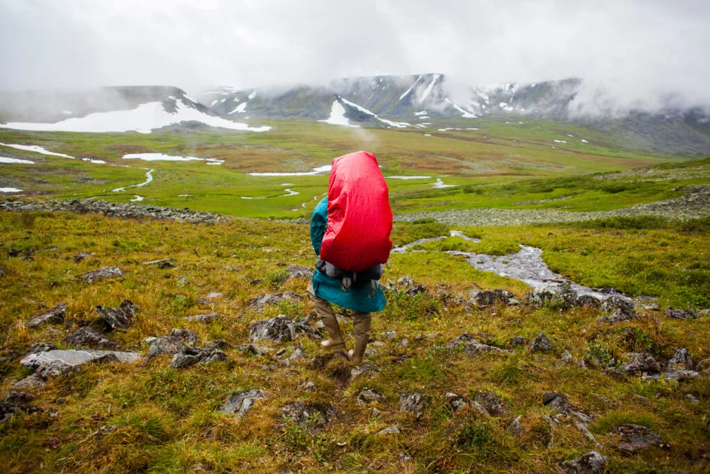 Lightweight rain shell draped over a backpack in wet weather