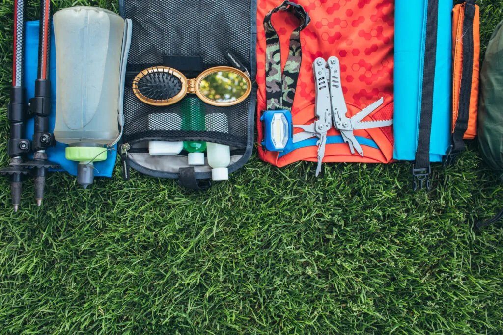 Repair kit and multi-tools laid out flat alongside hiking equipment