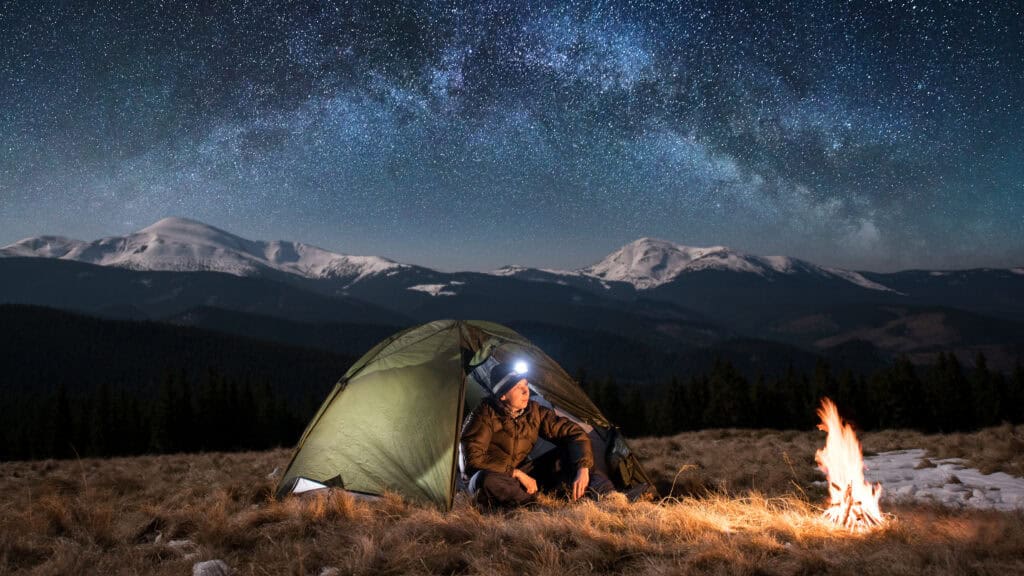 A headlamp glowing in low light on a camping setup.