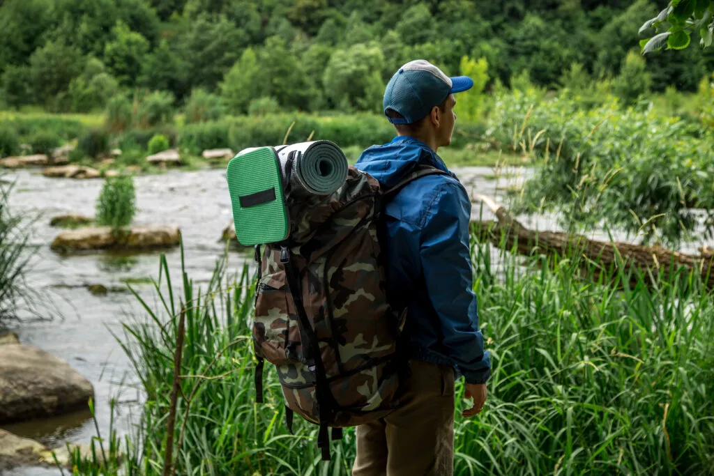 Bugout bag hike, a young guy with a Hiking backpack on his shoulders, the concept of travel and summer vacation