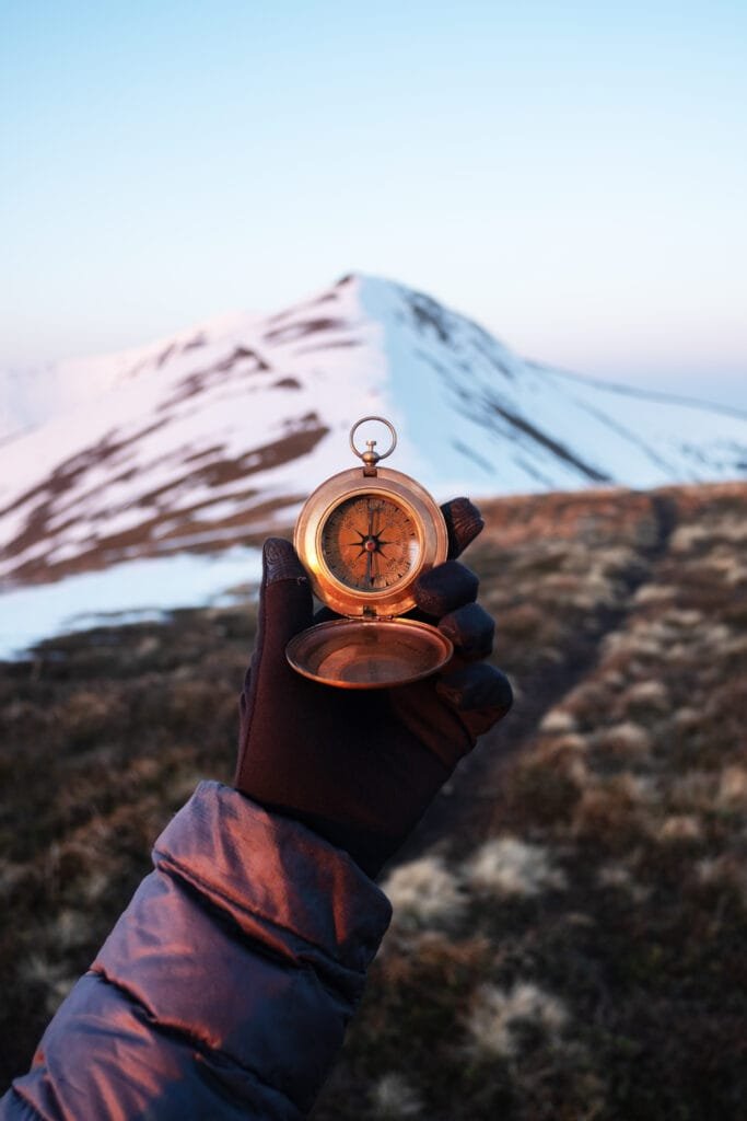 Declination matters, Man with retro compass in hand in high mountains. Travel concept. Landscape photography