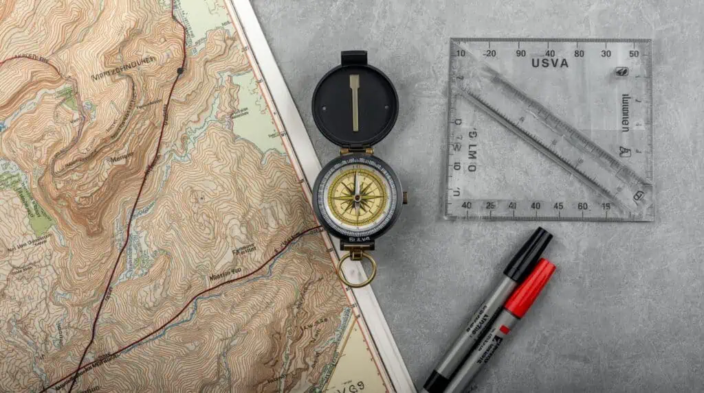 Topographic map with compass, protractor, and markers for outdoor adventure navigation and hiking planning.