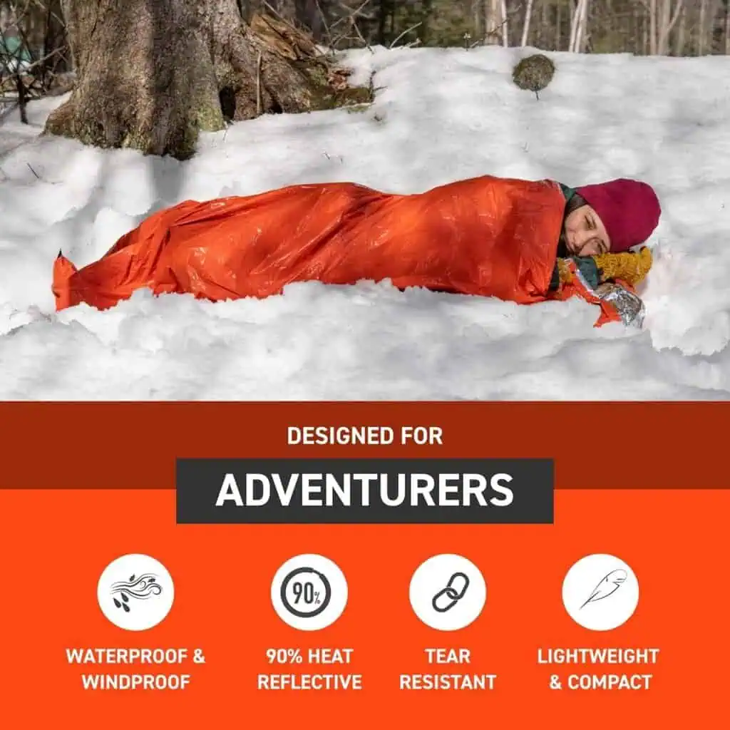 Person resting in a waterproof, lightweight survival sleeping bag in snowy forest, designed for preppers and outdoor adventurers in harsh winter conditions.