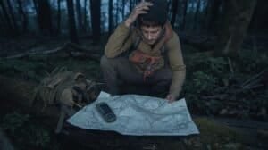 Man studying a topographic map in a dense forest to avoid land navigation mistakes during outdoor adventures.